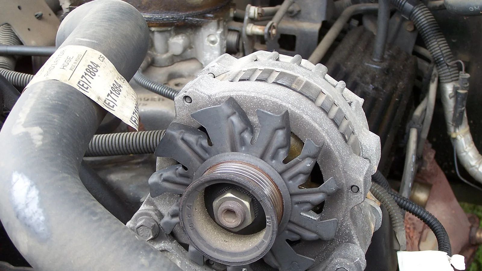 Alternador automotivo instalado no motor de uma picape, com polia e ventoinha em destaque